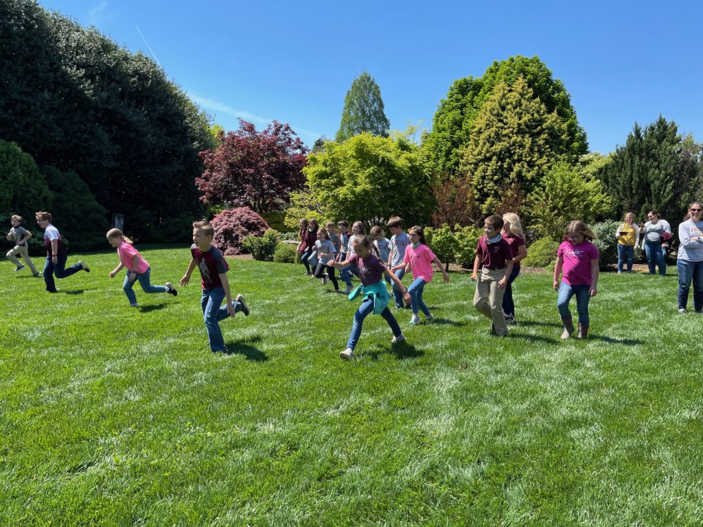 Children running through a field of green grass.