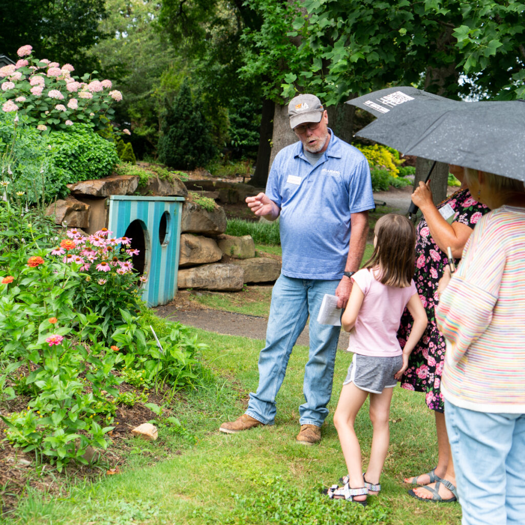 Man speaking to children and adults in a garden