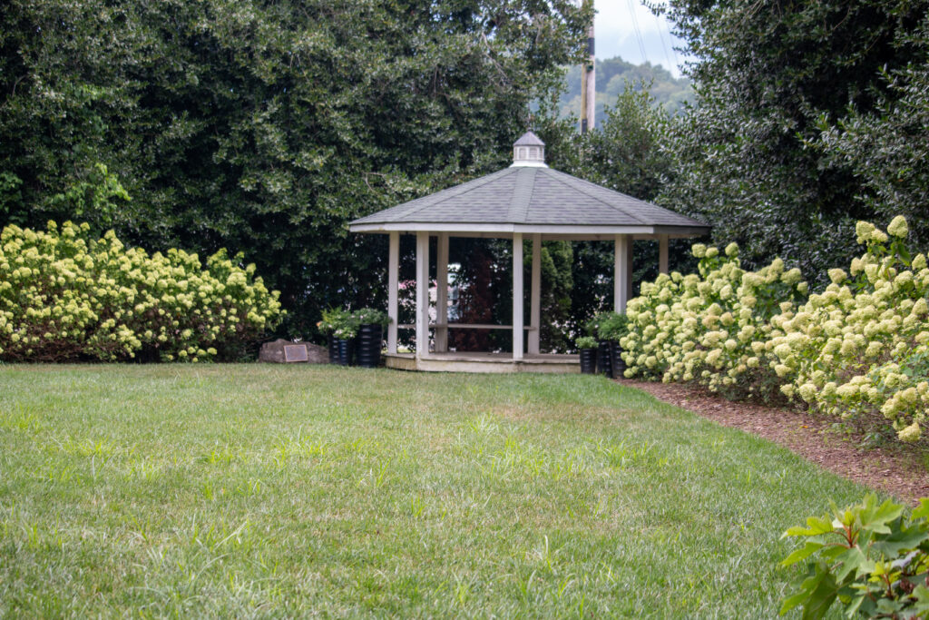 An open-walled gazebo flanked by Hydrangea shrubs on either side