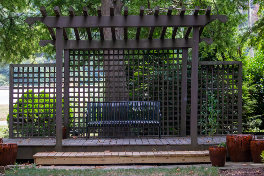 Wooden stage with bench covered by wooden pergola is the main fixture in the hosta garden