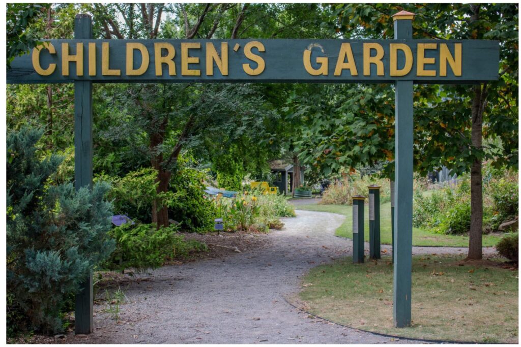 children's garden on green sign in yellow lettering marking the entrance to this garden area