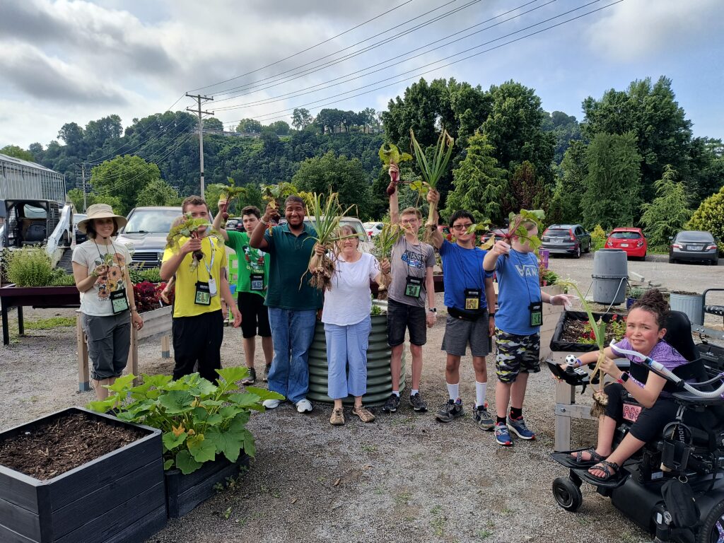 Group photo of many people smiling and holding plants