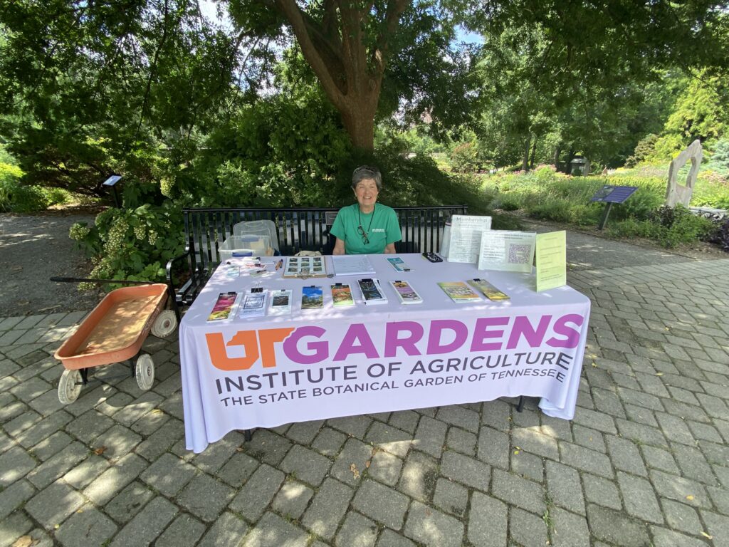 a volunteer heads the greeter table with information for guests at the main entrance of the gardens plaza