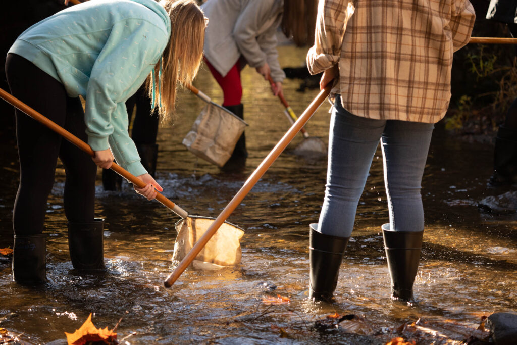 image of adults wearing wading boots in a stream with nets
